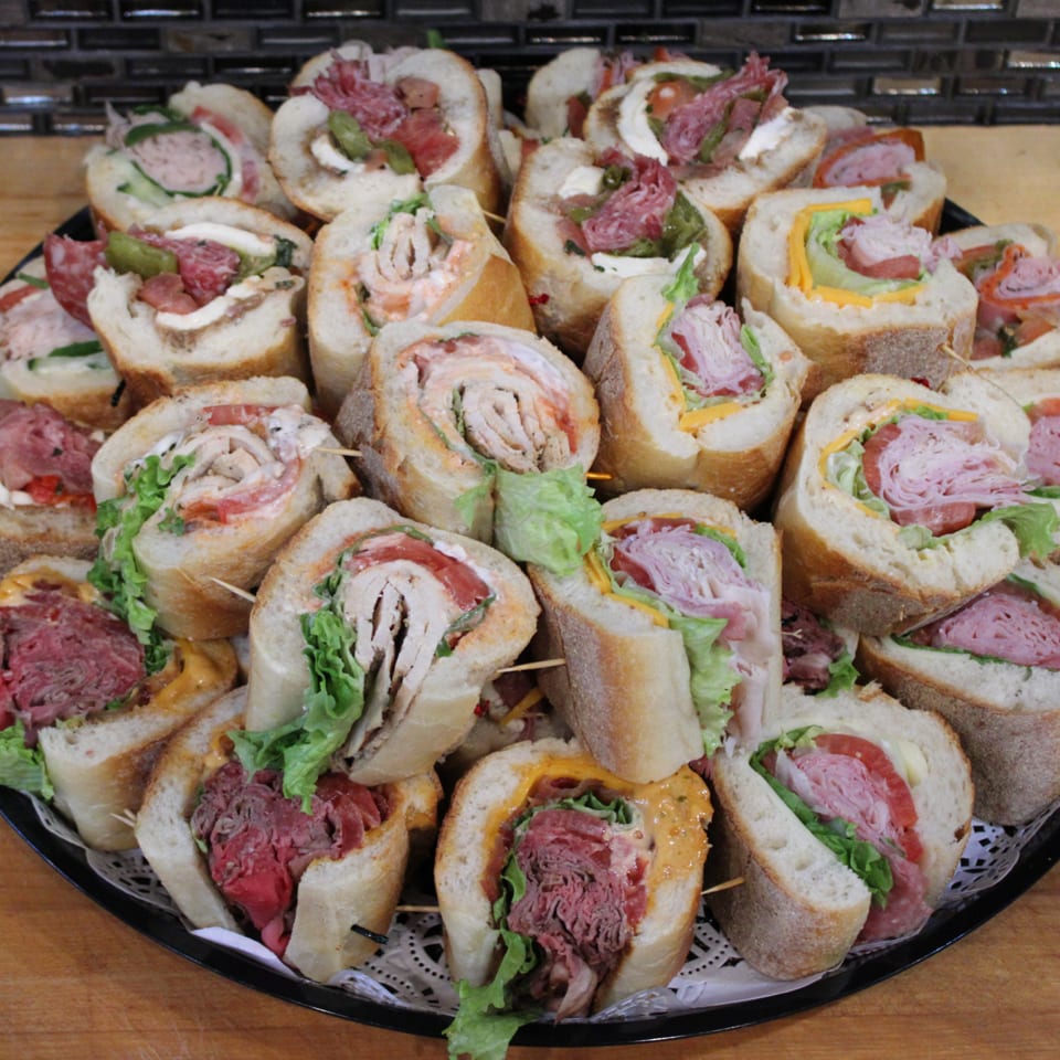 A large platter filled with various baguette sandwich halves, each secured with a toothpick.