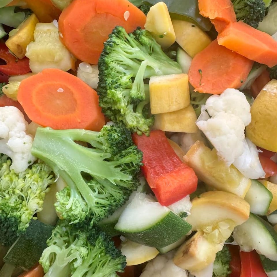 Close-up of colorful chopped vegetables including broccoli, carrots, zucchini, bell peppers, and cauliflower.