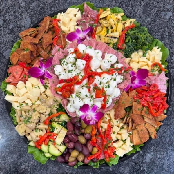 A large charcuterie board filled with meats, cheeses, olives, vegetables, and mozzarella balls.