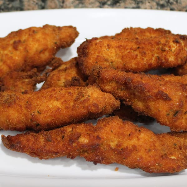 Golden-brown fried chicken tenders, breaded and seasoned, arranged on a white plate.