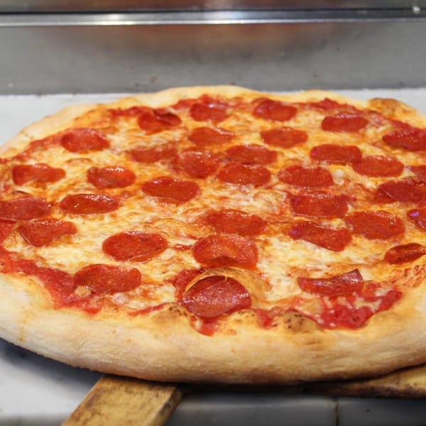 Freshly baked pepperoni pizza with melted cheese and red sauce on a wooden peel.
