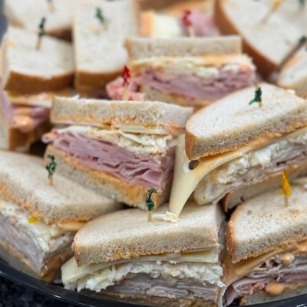 Platter of assorted deli sandwiches, cut into triangles and held with toothpicks.