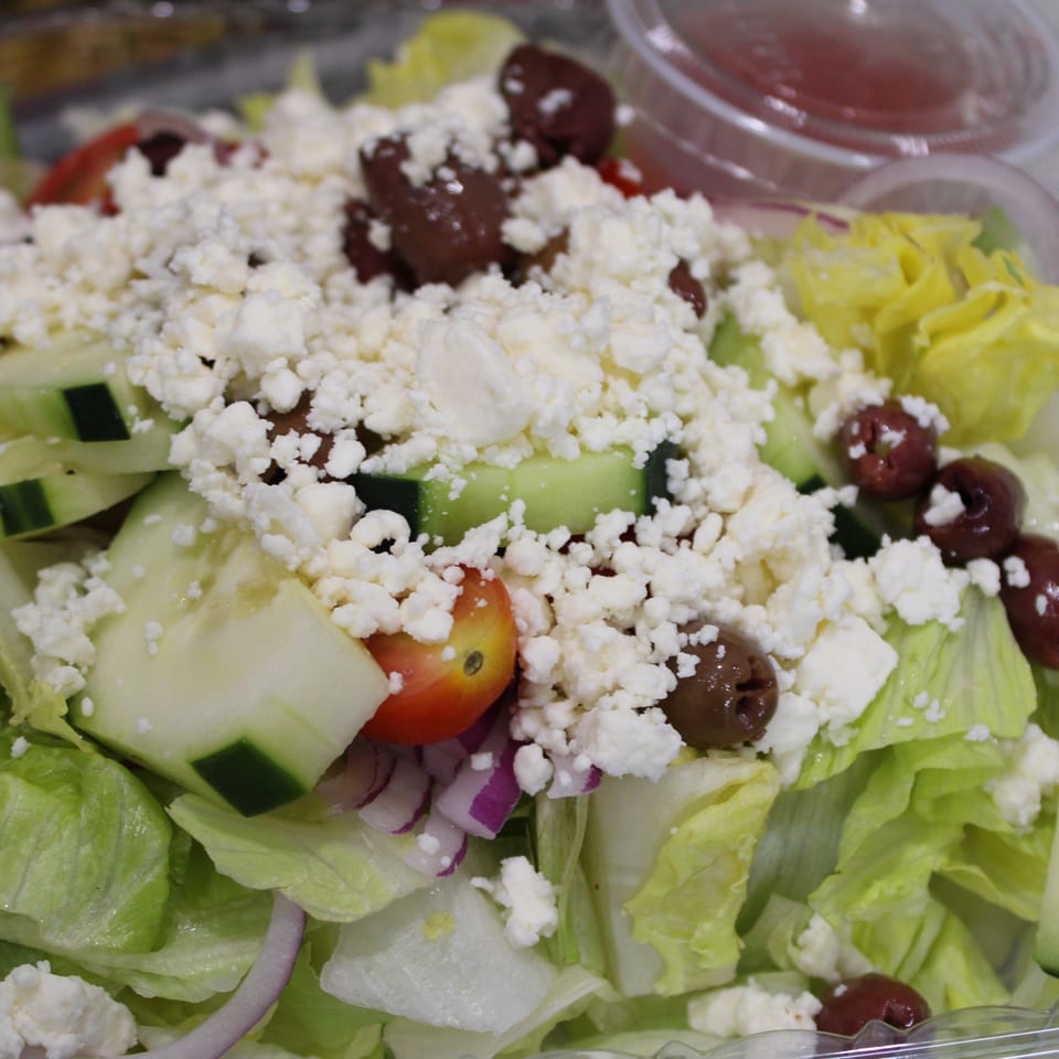 Close-up of a vibrant Greek salad with feta, olives, cucumbers, tomatoes, and red onion.