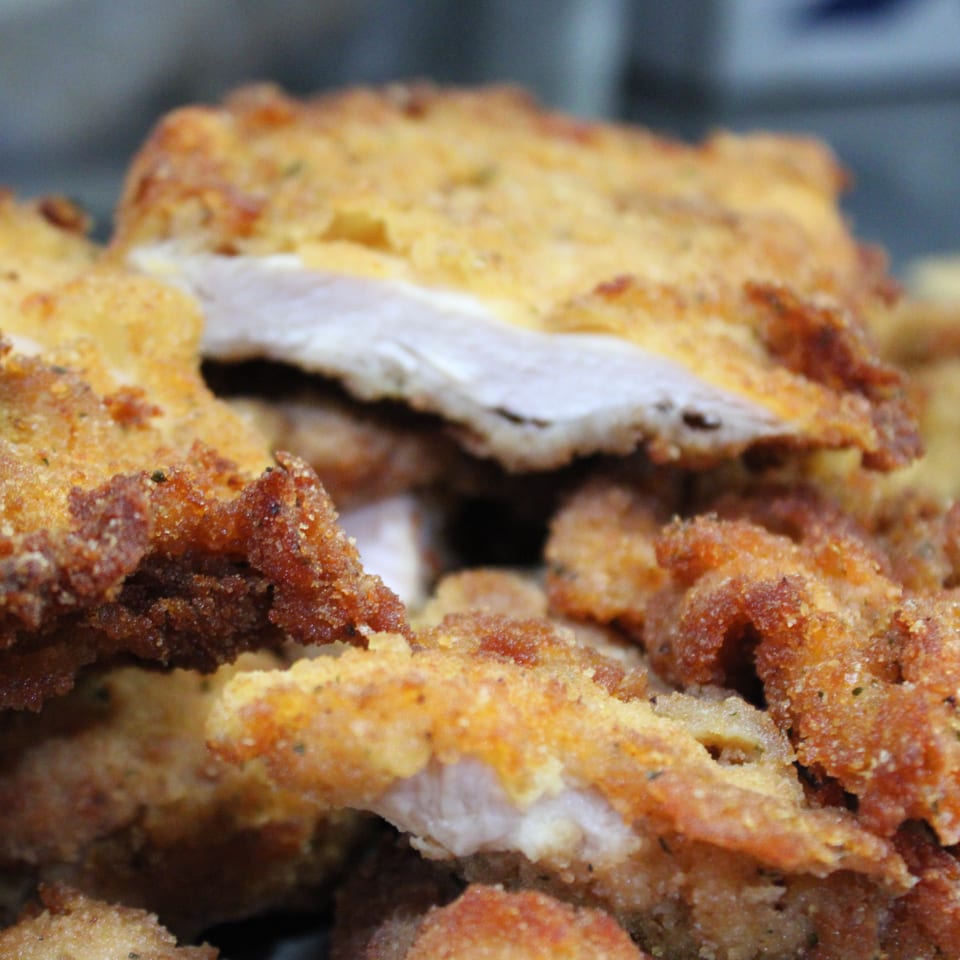 Close-up of crispy, golden-brown fried chicken pieces, some revealing tender white meat.